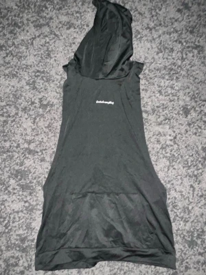 Svart ärmlös topp med huva - Cool svart ärmlös topp med huva och vit texten 'Controls everything' på bröstet. Perfekt för en avslappnad streetwear-look. Tunn och mjuk känsla, passar till många olika stilar.