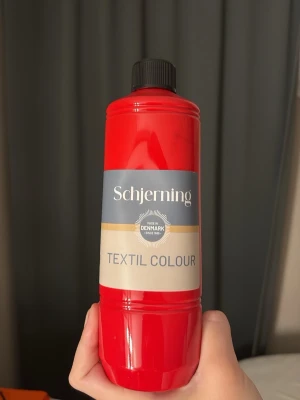 Röd textilfärg  - Säljer en flaska röd textilfärg från Schjerning. Perfekt för att färga eller måla på ljusa tyg och textilier. Flaskan är av plast och har svart skruvlock. Tillverkad i Danmark. Använd en gång till en tröja💋
