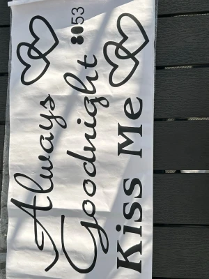 Väggdekor Always Goodnight Kiss Me - Säljer en svartvit väggdekor med texten 'Always Goodnight Kiss Me' och hjärtmotiv. Perfekt för att skapa en mysig känsla i sovrummet. Instruktioner för applicering medföljer. Dekoren är i plastmaterial och enkel att sätta upp. ca 26cm hög 50cm bred