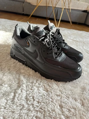 Nike Air Max 90 cordura svarta sneakers - Helt oanvända Snygga svarta Nike Air Max 90 sneakers med gore tex material som gör dem vattenavvisande. Skorna har en klassisk siluett, robust sula och detaljer i både textil och läder. Perfekta för dig som vill ha stilrena och funktionella sneakers.