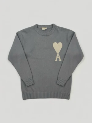 Ami Paris Ami de Coeur - Säljer en blå stickad tröja från Ami Paris med ett vitt hjärta och bokstaven A broderat på bröstet.  Tröjan har rund halsringning och ribbade muddar och nederkant.  En perfekt tröja för dig som uppskattar stilrena detaljer och klassisk design. 