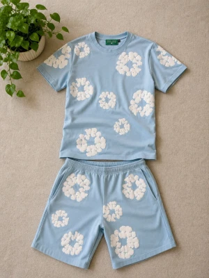 Blått set från Denim Tears - Säljer ett ljusblått set från Denim Tears med t-shirt och shorts. Båda plaggen har vita molnliknande tryck över hela ytan. T-shirten har rund hals och korta ärmar, shortsen har resår i midjan och sidofickor. Perfekt för en chill och avslappnad stil. Materialet och kvaliteten är sjuktbra, snören finns på insidan av shortsen.