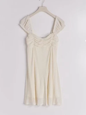 Mini dress Gina tricot - Söt creme vit mini dress med puffärmar och rynkade detaljer vid bysten. Klänningen har en lätt utsvängd kjol och är tillverkad i ett tunt, strukturerat tyg som ger en luftig känsla. Perfekt för varma dagar och somriga tillfällen.