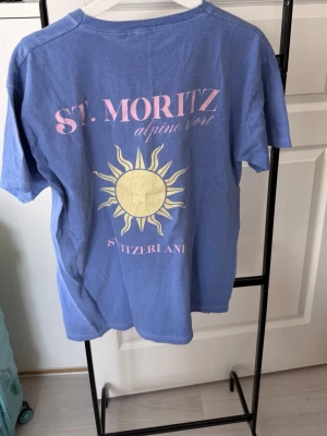 Blå basic t-shirt från Boohoo - En enkel blå t-shirt från Boohoo i storlek M. T-shirten har rund halsringning och korta ärmar. Tillverkad i mjuk bomull för en skön känsla. Perfekt till jeans eller shorts för en avslappnad look.