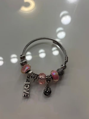 Pandora liknande armband med rosa pärlor - Snyggt armband i silverfärg med flera detaljerade berlocker, aldrig använt så fint skick.