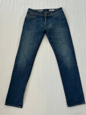Blå raka jeans från Jacob cohen - Snygga blå jeans från Jacob Cohen i modelen Nick PRMJ.  Lätt tvättad look. Storleken W 33 L 34. Observera att framknappen saknas men går att sy på en ny lätt.