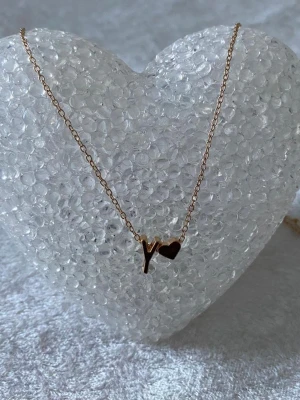 Guldhalsband med bokstav och hjärta - .Perfekt för dig som vill ha ett personligt smycke med enkel och stilren design. Halsbandet är i metall och har en modern känsla. A-Z kvar , helt ny 99kr/st 