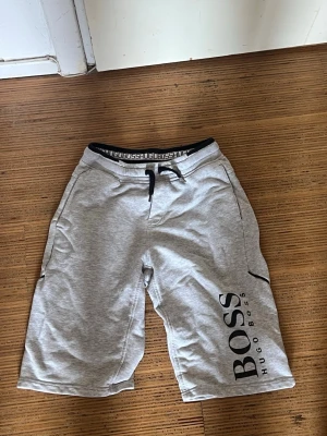 Grå shorts från Hugo Boss storlek 160 14 år S  - Snygga grå shorts från Hugo Boss med svart snörning i midjan och stort BOSS-tryck super bra skick 150 kr frakatar samma dag !