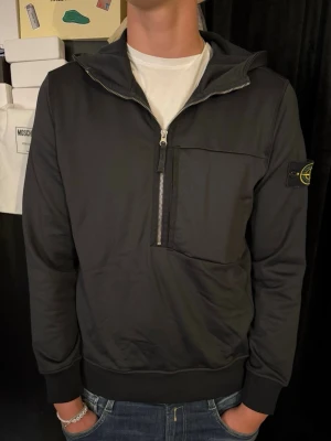 Svart hoodie från Stone Island - ÄKTA Stone Island svart hoodie med halv dragkedja framtill och stor bröstficka. Knappt använd och nypris är ca 4000 kr. Storlek S.