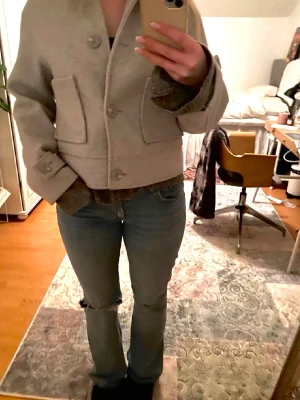 Ljusblå bootcut jeans med slitning - Säljer ett par ljusblå bootcut jeans i klassisk femficksmodell. Jeansen har en tydlig slitning vid ena knät och är tillverkade i denim. Snyggt avslappnad passform med lätt utsvängda ben som ger en trendig vibe.