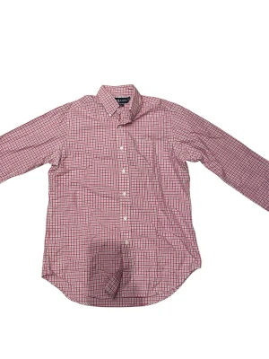 Vintage rutig skjorta från Ralph Lauren - Klassisk rutig skjorta från Ralph Lauren i rosa, vitt och blått. Skjortan har lång ärm, knappar framtill och button-down krage. Tillverkad i mjuk bomull och har en avslappnad passform. Perfekt för en stilren och tidlös look.