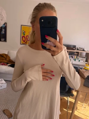 Beige ribbad topp med öppen rygg - Säljer en beige långärmad topp med ribbad struktur. Toppen har en snygg öppen rygg med knytband som detalj. Perfekt för dig som vill ha något stilrent men ändå unikt. Passformen är normal och materialet känns mjukt och stretchigt.