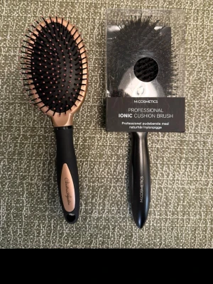 Nya hårborstar - Säljer två nya hårborstar, Christina Aguilera oval borste med svart och roséguld handtag samt en M.COSMETICS Professional Ionic Cushion Brush med svarta borst och ergonomiskt handtag. Perfekta för att reda ut håret och ge en snygg finish.