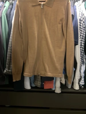 Beige ziptröja med krage - Snygg beige ziptröja med krage och långa ärmar. Storlek M, inte använt. Hör av dig för bilder eller liknade. Från J.Lindberg 
