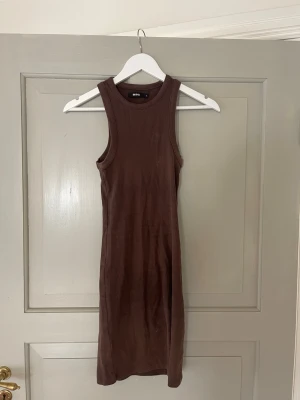 Brun ribbad klänning från BikBok - Säljer en brun, ribbad klänning från BikBok i storlek S. Klänningen är ärmlös, har rund halsringning och är i en mjuk, stretchig bomullsblandning. Perfekt för en enkel och stilren look.
