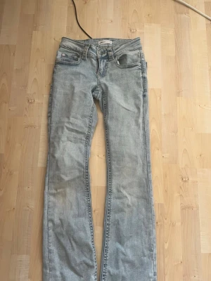 Ljusblå bootcut jeans - Säljer ett par ljusblå jeans med bootcut passform och klassiska fem fickor. Jeansen har snygga detaljer på bakfickorna och är tillverkade i ett mjukt denimtyg. Perfekta för en avslappnad och trendig look. Buda!! Skickar idag!