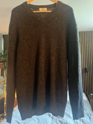 Valentino Mörkbrun stickad tröja - Valentino Mysig mörkbrun stickad tröja med rund halsringning och långa ärmar. Tröjan har en enkel, klassisk design och ribbstickade muddar vid ärmslut och nederkant. Perfekt för kyliga dagar och lätt att matcha med olika outfits.