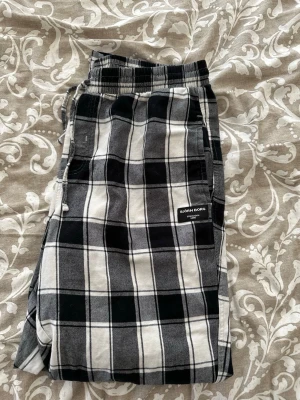 Rutiga pyjamasbyxor från Björn Borg - Säljer ett par svartvita rutiga pyjamasbyxor från Björn Borg. Byxorna har resår i midjan och är gjorda i mjukt bomullstyg. Perfekta för chill hemma eller mysiga kvällar. Klassisk passform med fickor på sidorna och diskret logga på benet. Byxorna har små defekter (se sista bilden). Den totala längden är 98cm