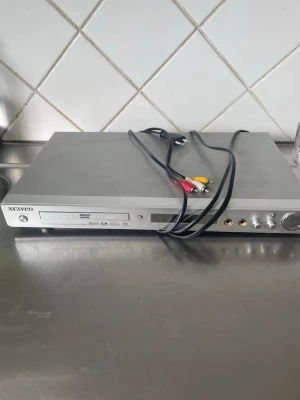 Samsung DVD-spelare DVD-P650K - Säljer en silverfärgad Samsung DVD-spelare, modell DVD-P650K. Den har en slimmad rektangulär design och kommer med RCA-kablar för anslutning till TV eller ljudsystem. Perfekt för att spela DVD-filmer och musik hemma.