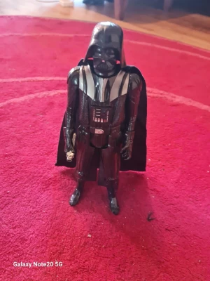 Darth Vader figur från Star Wars - Cool Darth Vader figur från Star Wars i svart plast med detaljer i silver. Figuren har en ikonisk hjälm, mantel i tyg och detaljerad dräkt. Perfekt för samlare eller som dekoration för alla Star Wars-fans.