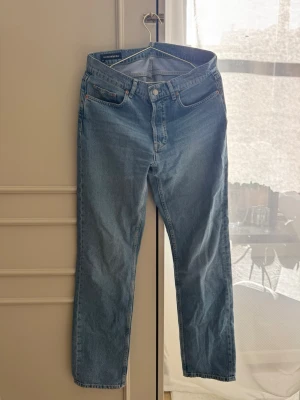 Blå raka jeans från J.Lindeberg - Snygga blå jeans från J.Lindeberg i klassisk rak modell. Jeansen har fem fickor, knappgylf och är tillverkade i slitstark denim. Perfekta för dig som gillar en tidlös och clean look.