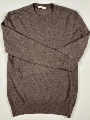 Suitsupply Pure 100% Cashmere Tröja Brun Storlek S - Exklusiv brun crewneck-tröja i 100% cashmere från Suitsupply.  Mjuk, finstickad och i mycket fint skick  B Grade) med ribbade muddar. Figurnära och skön passform.  Tveka inte att höra av dig vid frågor eller funderingar.   Mått [platt] :  A: 61 cm B: 62 cm C: 40 cm  OBS: Sitter för litet och för tight på killen i bilden! Skickas snabbt!