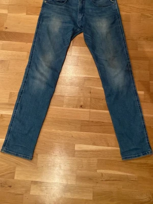 Blå halvwashed Replay anbass jeans - Säljer ett par replay anbass med raka ben och diskreta slitningar på framsidan och baksidan. Jeansen har fem fickor och normal midja. Storlek W31, L32. Passformen är avslappnad men ändå snyggt åtsittande.