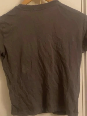 Mörkgrå basic topp - En enkel mörkgrå topp med rund hals och korta ärmar. Perfekt till jeans eller shorts för en avslappnad look. Tillverkad i mjukt bomullsmaterial som känns skönt mot huden.