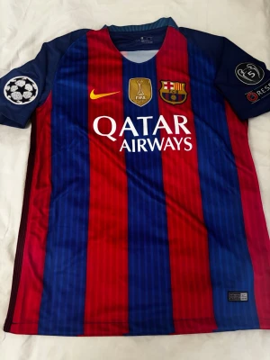 FC Barcelona Neymar Jr matchtröja - Säljer en officiell FC Barcelona matchtröja från Nike med Neymar Jr och nummer 11 på ryggen. Tröjan har blå och röda vertikala ränder, Champions League-märke på ärmen och Qatar Airways som sponsor framtill. Tillverkad i lätt och ventilerande polyester.