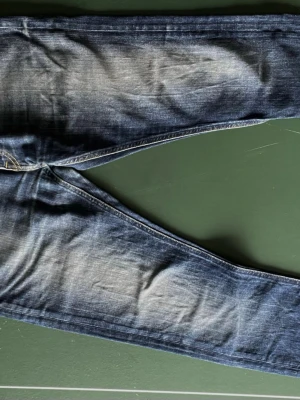 Blå jeans från Lee  - Säljer ett par klassiska mörkblå jeans från Lee med snygga  kontrastsömmar i strl 30/32. Jeansen har en rak passform och är tillverkade i slitstark denim. Perfekta för en avslappnad och trendig look.