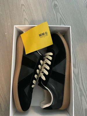 Maison Margiela svarta sneakers - Svarta sneakers från Maison Margiela  och levereras i originalkartong med dustbag. Storlek 42. 