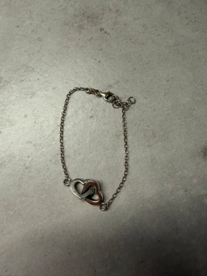 Armband med hjärthänge i sterling silver  - Snyggt armband i sterling silver med ett dubbelt hjärthänge, finns silver stämpel 925 på armbandet. 
