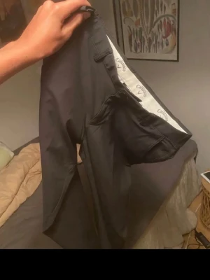 Svarta byxor från Callaway - Snygga svarta byxor från Callaway med klassisk passform och diskreta fickor. Insidan har ett ljust foder med små mönster och logga. Perfekta för dig som vill ha en stilren och bekväm look till vardags.