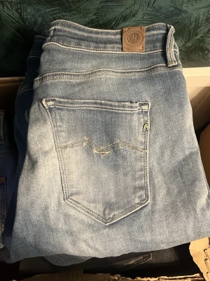 Replay jeans  - Säljer ett par blå Replay jeans. OBS jeansen har ett hål på ena knät. Midja 36cm, längd 99cm. JAG SKICKAR EJ FLER BILDER NÄR JAG BÄR JEANSEN! för bättre inblick i passformen rekommenderar jag att googla på modellnamnet. För storleksguide kolla måtten noggrant då jeansen alltid kan vara uppsydda heller krympta och jag ej tar emot returer :) r22