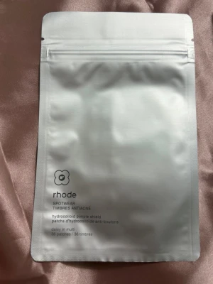 Rhode hydrocolloid pimple patches - Rhode Spotwear hydrocolloid pimple shield är genomskinliga plåster för punktbehandling av finnar. Förpackningen innehåller 36 plåster i olika former och storlekar, perfekta för att dölja och behandla blemmor diskret.