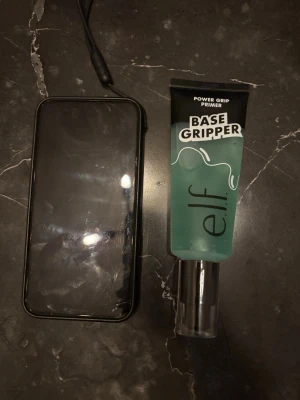 e.l.f. Base Gripper Power Grip Primer - Power Grip Primer från e.l.f. i en genomskinlig tub med svart lock. Primern har en blågrön geléliknande konsistens och är designad för att ge sminket extra fäste. Tuben har tydlig text och modern design, perfekt för att skapa en jämn bas. ( stor tub )