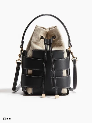 SÖKERRR!!! Beige och svart bucket bag - Trendig bucket bag i beige canvas med svarta läderdetaljer och vita sömmar. Väskan har justerbar axelrem, guldfärgade metalldetaljer och dragskostängning. Perfekt för dig som vill ha en cool och modern look.