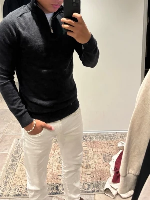 Mörkgrå halvzip tröja - Mörkgrå stickad tröja med halv dragkedja och hög krage. Tröjan har långa ärmar och ribbade muddar vid ärmslut och nederkant. Perfekt för lager-på-lager och enkel att matcha med olika outfits. Storlek M men passar bra för S 