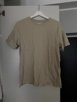 Beige Bomulls T-shirt - Take Off - Säljes då min sambo ej använder denna längre! Den är använd några enstaka gånger så i väldigt fint skick. Lite skrynklig pga legat i garderoben. 😁 Skulle säga att den är normal i storleken. 🌸