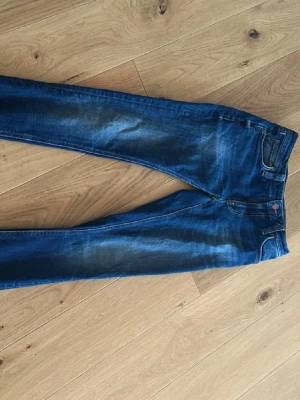 Nudie jeans - Snygga blå skinny jeans med lätt slitna detaljer och tvättade partier på låren och knäna. Klassisk femficksmodell med normal midja och smal passform. Perfekta till en avslappnad och trendig look.