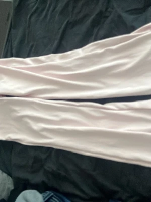 Ljusrosa leggings med stretch - Säljer ett par ljusrosa leggings med smal passform och stretchigt material. Perfekta för en avslappnad och bekväm stil. De har en enkel design utan synliga detaljer eller mönster.