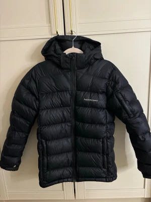 Peak Performance - Frost Down  - Säljer en Peak Performance Frost Down-jacka i storlek 170. Jackan är i mycket fint skick och har knappt några tecken på användning (se bilder), då den mestadels har hängt i garderoben. Fylld med 90 % ankdun och 10 % fjäder, vilket gör den både varm och lätt – perfekt för höst och vinter.                                                                      Köpt på Intersport.                                           Nypris: 2 699 kr.
