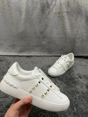 Valentino Rockstud/ Opens - vit/guldiga - Tjena! Säljer nu dessa valentino rockstuds. Helt nya, aldrig använda. Skicket är 10/10. De är vita med guldiga spikar. Storlek 38, passar 37/39. Så fråga gärna. Priset går att diskretas vid snabbaffär 💕