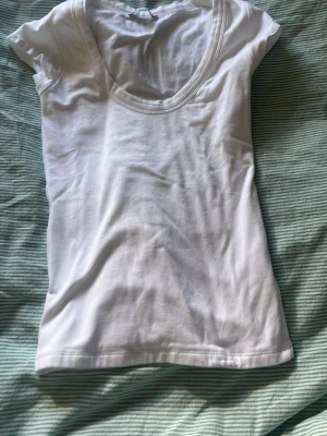 Vit basic t-shirt med rund hals - En enkel vit t-shirt med rundad halsringning och korta ärmar. Tillverkad i mjuk bomull som känns skön mot huden. Perfekt att matcha med jeans eller shorts för en clean och fräsch look. Helt oanvänd💕