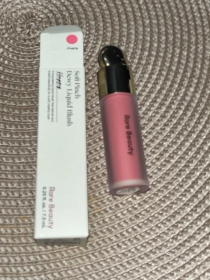 Rare Beauty Soft Pinch Dewy Liquid Blush - Rare Beauty Soft Pinch Dewy Liquid Blush i nyansen Happy. Flytande rouge i en fräsch rosa färg med dewy finish. Kommer i en stilren frostad tub med guldfärgat lock och tillhörande kartong. Perfekt för en naturligt glowig look.