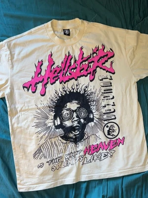  Hellstar Records t-shirt - Säljer en vit Hellstar t-shirt med stort Hellstar Records-tryck fram och bak. Framsidan har ett grafiskt motiv i svart och rosa med text och illustration, medan baksidan har en stor logga. Klassisk passform och rund hals, perfekt för dig som gillar streetwear och statement-plagg.