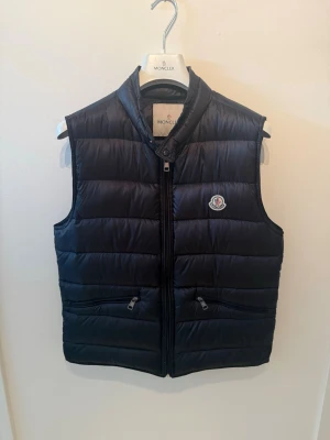 Moncler Gui  - Säljer nu denna fina Moncler gui väst i strl 3 vilket motsvarar M. Fint skick. Kvitto på Mail finns! Självklart äkta! 