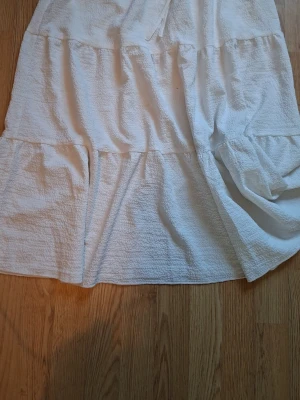 Vit långkjol i bomull med volang💗 - Säljer en vit långkjol i mjukt bomullstyg. Kjolen har volangdetaljer och en avslappnad passform med resår i midjan. Perfekt för varma dagar och enkel att styla med olika toppar. Typ använd 1 gång för passade inte mig så bra så väldigt bra skick🤗