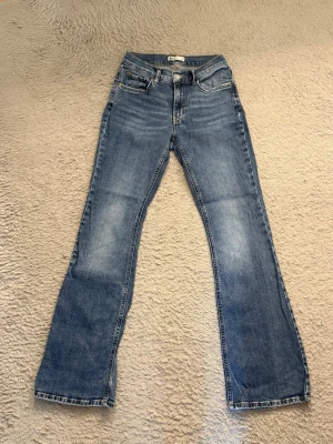 Bootcut jeans - Säljer dessa snygga bootcut jeans med låg midja. Jeansen har en snygg tvätt med lätt slitningsfärg på låren/knäna och raka ben som går ut lite nedtill. Perfekta till sneakers eller boots och gjorda i mjuk denim med stretch. Väl använd men i gott skick!