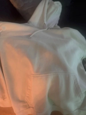 Beige hoodie med magficka - En enkel och stilren beige hoodie med huva och dragsko. Hoodien har en stor magficka framtill och är gjord i mjukt bomullsliknande material. Perfekt för en avslappnad och chill look.